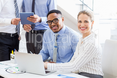 Business colleagues using laptop and digital tablet at desk