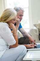 serious senior couple using laptop at home