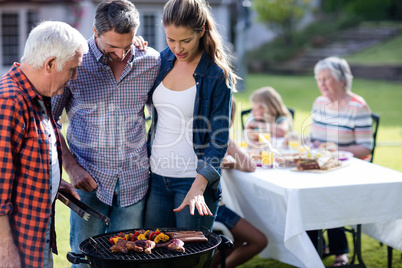 Couple and a senior man at barbecue grill preparing a barbecue