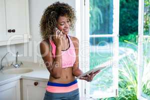 Woman looking at digital tablet while talking on phone