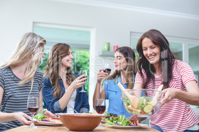 Friends holding glass of red wine while having meal