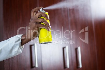 Hand spraying pesticide from a spray can