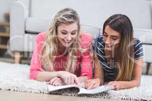 Two beautiful women reading a magazine in living room