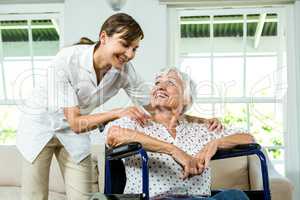 Happy nurse looking at senior woman sitting on wheelchair