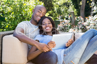 Young couple relaxing on the sofa and using digital tablet