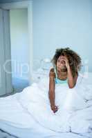 Tensed woman sitting on bed in bedroom