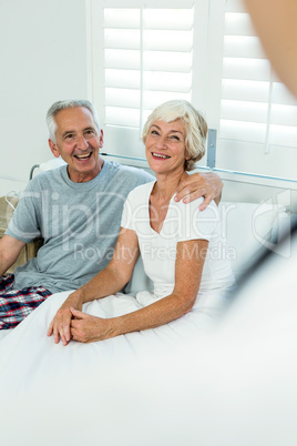 Happy senior couple sitting on bed