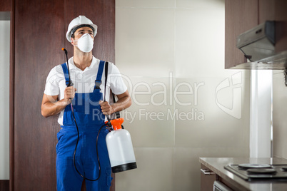 Front view of pest worker spraying in kitchen