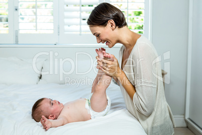 Mother playing with baby boy lying on bed