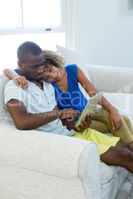 Young couple using a digital tablet in living room