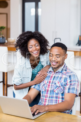 Happy young couple using laptop in kitchen