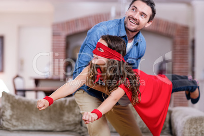 Father and daughter pretending to be superhero in living room