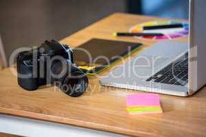 Camera, sticky notes, graphics tablet and laptop at desk