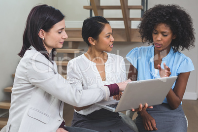 Female business colleagues discussing on laptop