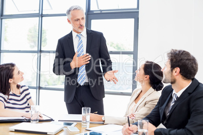 A businessman is standing in front of his colleagues and talking