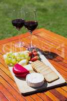 Wine glass, fruit, cheese, biscuits on wooden table