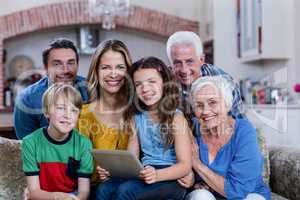 Portrait of multi-generation family sitting on sofa and using di