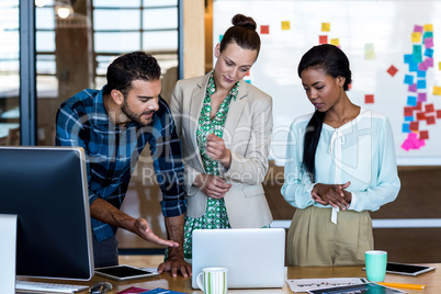 Young man and women discuss using laptop