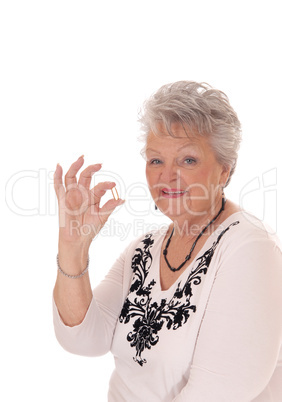 Senior woman holding vitamin pill.