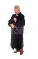 Senior woman standing in fur coat.
