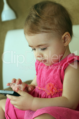 small kid plays with smartphone sitting on couch