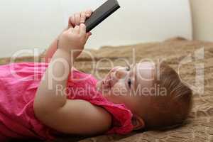 little smiling child playing with your smartphone lying on a sofa