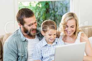 Parents and son using laptop in living room