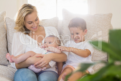 Mother sitting on sofa with her kids