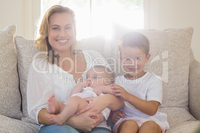 Portrait of mother sitting on sofa with her kids