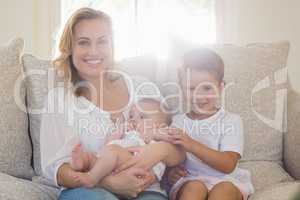 Portrait of mother sitting on sofa with her kids
