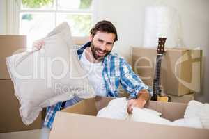 Portrait of young man unpacking carton boxes