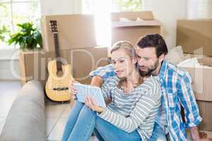 Couple sitting on floor and using digital tablet