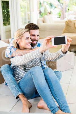 Couple sitting on floor and taking selfie in living room