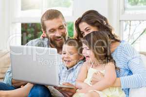 Parents and kids using laptop in living room