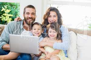 Portrait of parents and kids using laptop in living room