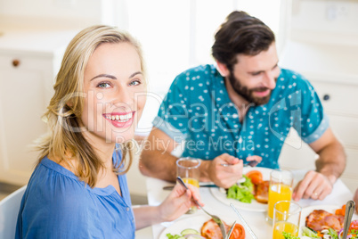 Beautiful young woman sitting at dining table smiling