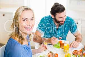 Beautiful young woman sitting at dining table smiling