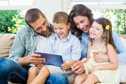 Parents and kids using digital tablet in living room