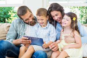 Parents and kids using digital tablet in living room