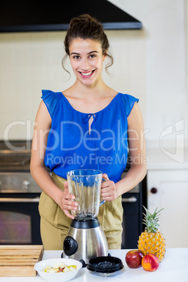 Happy young woman standing with mixer