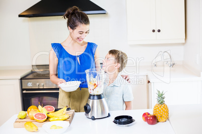 Mother assisting son to prepare juice