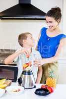 Mother assisting son to prepare juice