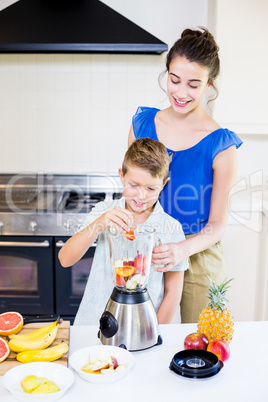 Mother assisting son to prepare juice