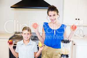 Mother and son holding fruits in kitchen