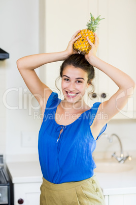 Portrait of young woman carrying pineapple on head