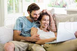Couple sitting on sofa and using laptop