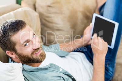 Portrait of man lying n sofa and using digital tablet