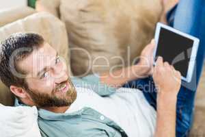 Portrait of man lying n sofa and using digital tablet