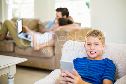 Portrait of boy sitting on sofa and using mobile phone