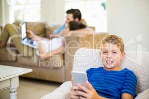 Portrait of boy sitting on sofa and using mobile phone